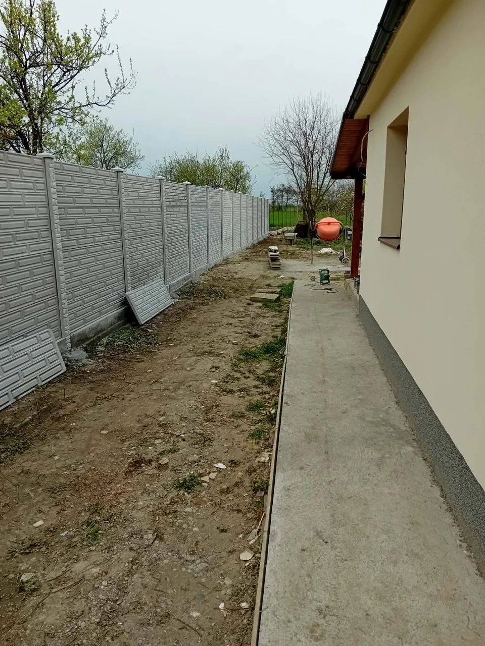 Gard lung din panouri de beton cu model dreptunghiular, montat lângă o locuință