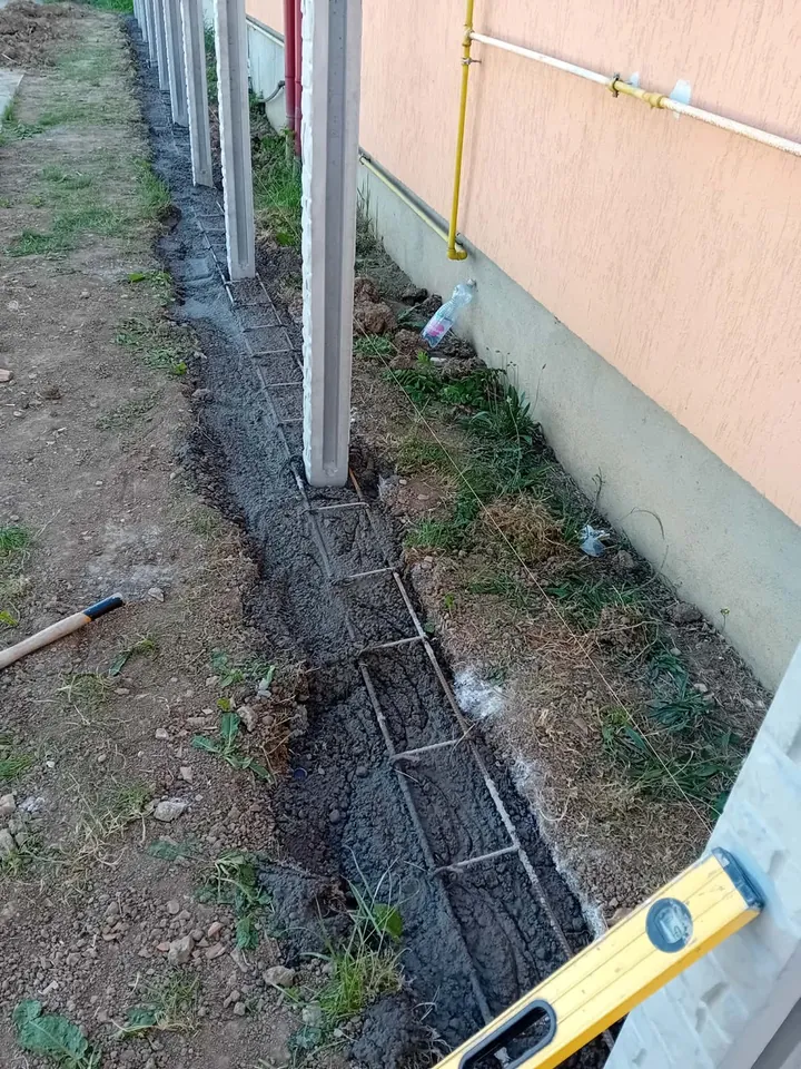 Stâlpi din beton poziționați lângă armătura fundației și betonul proaspăt turnat