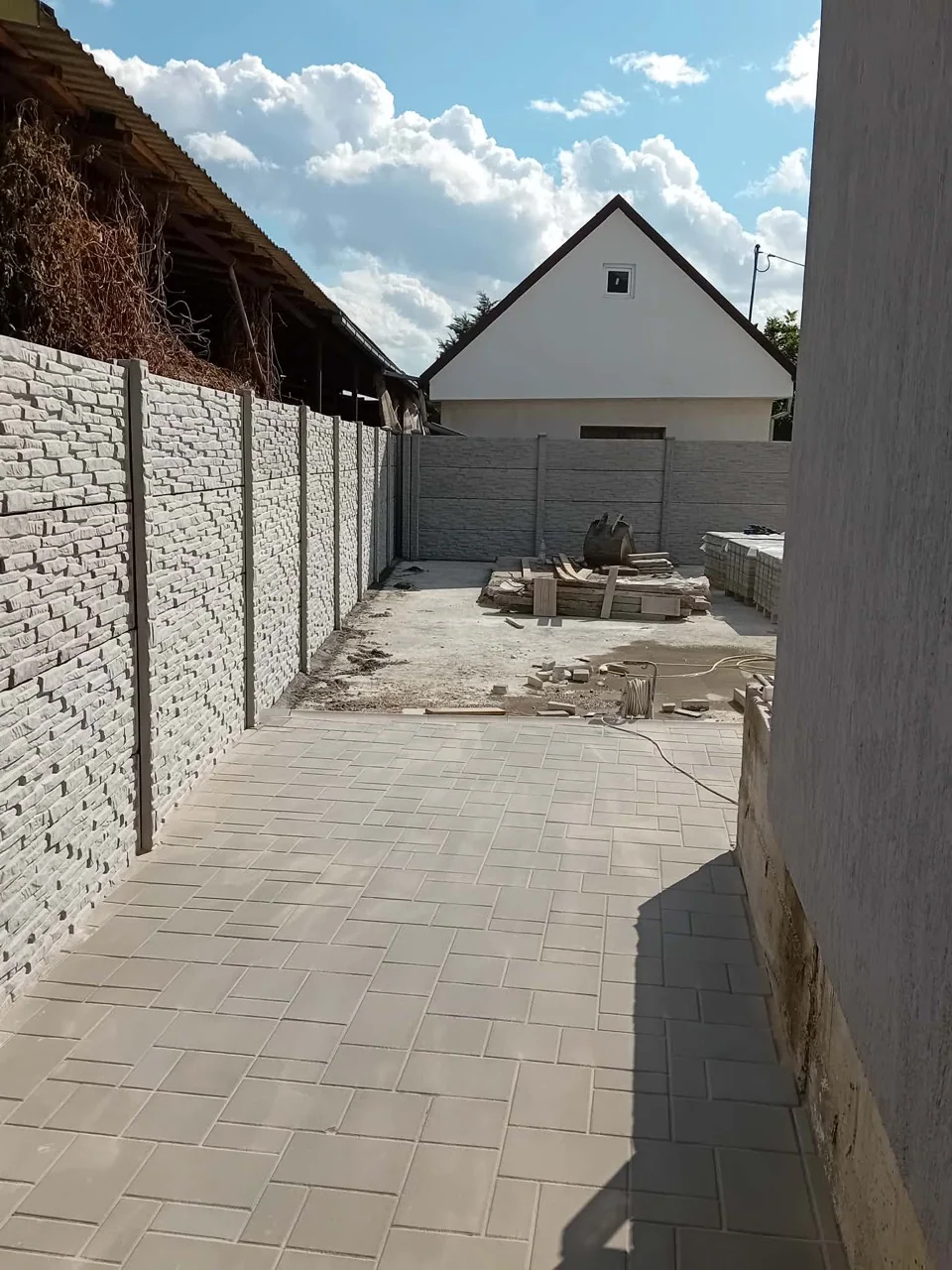 Panouri de gard din beton model Piatră Stratificată montate între stâlpi, în timpul amenajării curții
